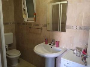 Un baño con lavabo, inodoro y espejo. en Apartman Dora, en Povljana