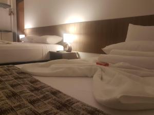 duas camas num quarto de hotel com lençóis brancos em Mamaloo Pousada em Maceió