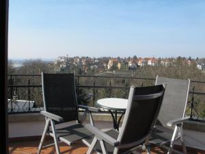 three chairs and a table on a balcony with a view at Ferienwohnung mit tollem Ausblick in Dresden +1 photo