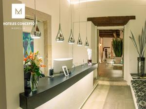 a hotel reception counter with flowers in a room at M Hoteles Concepto in Morelia
