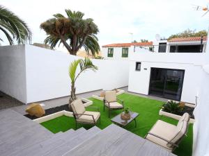 a patio with chairs and a lawn with palm trees at CASA BEATRIZ in La Orotava