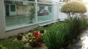 un jardin en face d'une maison avec une voiture près de la fenêtre dans l'établissement Praia do Forte: 5 min a pé, à Cabo Frio