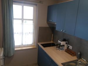 a kitchen with blue cabinets and a sink and a window at Neptun apartman in Dömsöd