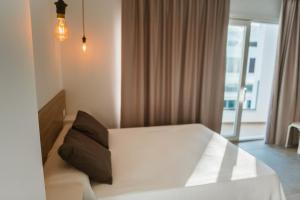 1 dormitorio con cama blanca y ventana en Apartamentos ZHR en Zahara de los Atunes