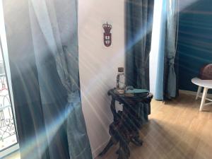 リスボンにあるOld Town Lx Suitesの青いカーテン、テーブル、窓が備わる客室です。