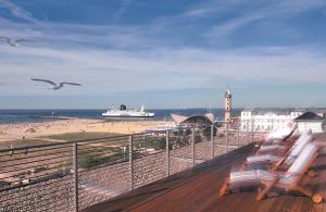 a beach with a cruise ship in the water at Strand-Hotel Hübner in Warnemünde