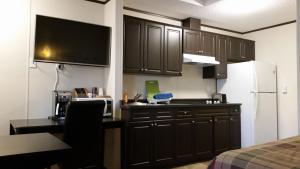 a kitchen with black cabinets and a white refrigerator at Bear's Den Lodge in Shaunavon