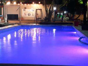 una gran piscina con luces moradas. en Cabañas Eterno Vergel en Mburucuyá