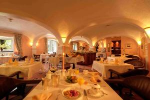 un restaurante con mesas blancas y sillas con comida. en Villa Garni Gardenia, en Caslano