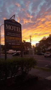 a sign for a motel with a sunset in the background at International Lodge Motel in Mackay