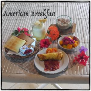 a table with a plate of breakfast foods and a drink at Bingin Bienvenue Guest House in Uluwatu