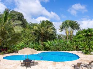a swimming pool with chairs and a table at Chachagua Rainforest Hotel & Hot Springs in Fortuna