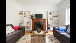 a living room with two couches and a fireplace at The Caretakers Cottage in Main Ridge