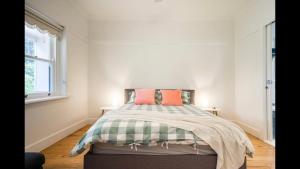 a bedroom with a bed with two orange pillows on it at The Caretakers Cottage in Main Ridge