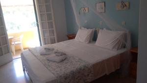 a bedroom with a white bed with towels on it at Aphrodite Studios & Pool in Paleokastritsa