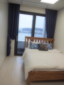 ein Schlafzimmer mit einem Bett und einem großen Fenster in der Unterkunft Nadree House 2 in Sokcho