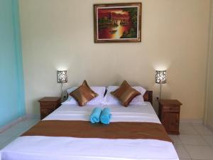 a bedroom with a white bed with two blue slippers on it at Repag Wayan Canggu Hostel in Canggu