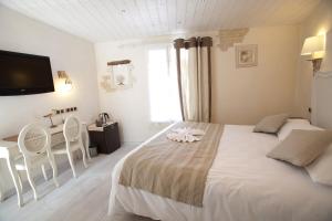 a bedroom with a bed and a table and a television at Chambre d'hôtes Hôte des Portes Île de Ré in Les Portes