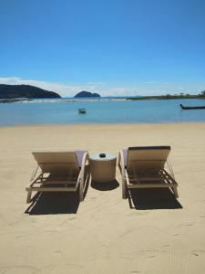 two lounge chairs and a table on a beach at Angkana Bungalows adults only in Thong Sala