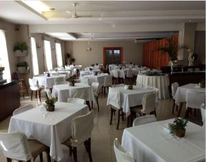 a dining room with white tables and white chairs at Hotel Dominguez Plaza in Nova Friburgo
