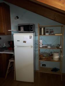 Elle comprend un réfrigérateur blanc et un four micro-ondes. dans l'établissement Appartamento LUCE, à Volpiano