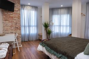 1 dormitorio con cama, escritorio y pared de ladrillo en Bienvenidos Rooms Xàtiva, en Xàtiva