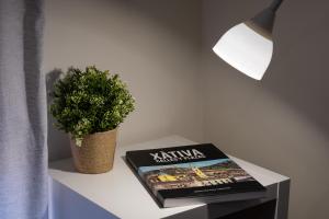 un livre sur une table à côté d'une plante en pot dans l'établissement Bienvenidos Rooms Xàtiva, à Xàtiva