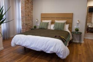 - une chambre avec un grand lit et un mur en briques dans l'établissement Bienvenidos Rooms Xàtiva, à Xàtiva