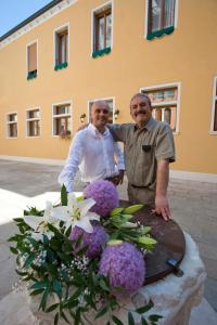 ヴェネツィアにあるホテル アル マルカントンの花のテーブルの横に立つ二人の年上の男