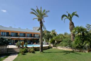 un complejo con palmeras y piscina en Hotel Cuor Di Puglia, en Alberobello