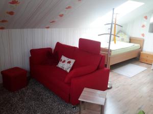 salon z czerwoną kanapą i łóżkiem w obiekcie Appartement Ferienwohnung Vogel w mieście Hilchenbach