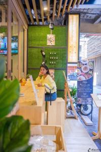 una joven sentada en una mesa en un restaurante en Kinnon Deluxe Hostel Coworking Cafe, en Bangkok