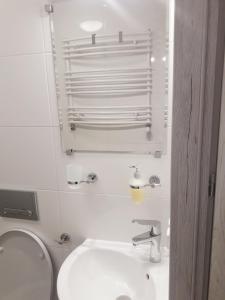 biała łazienka z toaletą i umywalką w obiekcie Pokoje Gościnne Plażowa w mieście Białystok