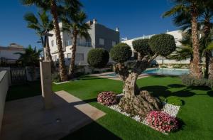 un jardín con un árbol y flores y un edificio en MarinaMed Residencial, Casa 2, en Orihuela