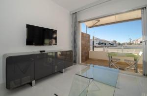 sala de estar con TV y mesa de cristal en MarinaMed Residencial, Casa 2, en Orihuela