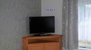 einen Flachbild-TV auf einem Holzständer neben einem Fenster in der Unterkunft Ferienappartements Am Weinberg in Bestensee