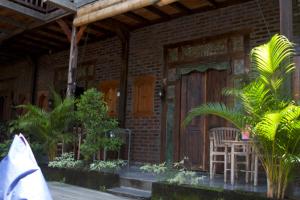 Casa con puerta de madera, mesa y sillas en Tropical Canggu Hostel en Canggu