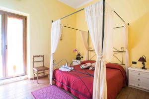 a bedroom with a canopy bed and a chair at B&B L'Albero Dei Limoni in Portoscuso