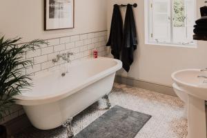 een badkamer met een wit bad en een wastafel bij Penny Black Cottage in Coalbrookdale