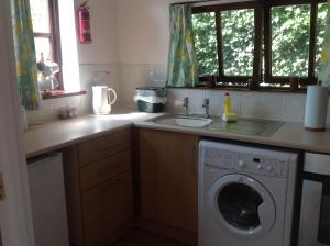 a kitchen with a washing machine and a sink at New Stable Cottage in Cowes