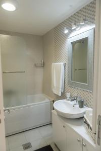 een badkamer met een wastafel, een bad en een spiegel bij Apartmani Hemera in Valjevo