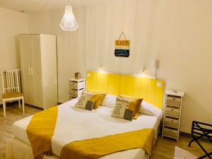 a bedroom with a large bed with a yellow headboard at Le Grand Hotel in Forcalquier