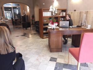 uma mulher sentada numa secretária com um portátil em Art Hotel Pietrasanta em Pietrasanta