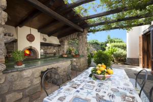 an outdoor kitchen with a table with a bowl of fruit at Amore Rentals - Residence Bosco in SantʼAgata sui Due Golfi
