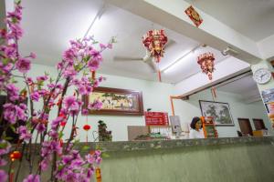 a woman sitting at a counter in a restaurant with purple flowers at Hotel Comfort Inn in Kluang