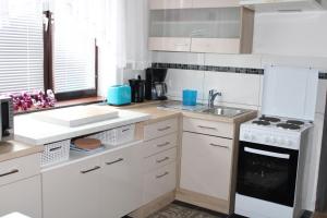 una cocina con armarios blancos y un horno de fogón blanco en Holiday House Huszar en Parndorf
