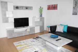 a living room with a black couch and a flat screen tv at Holiday House Huszar in Parndorf