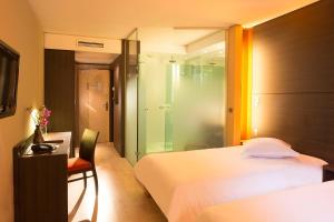 a hotel room with a bed and a glass shower at Oceania Quimper in Quimper