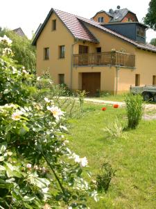 a house with a balcony and a yard with flowers at Ferienwohnung "Zur Wilke" in Stadt Wehlen