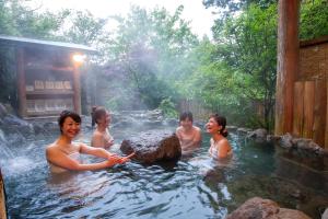 a group of people are in a hot tub at Kurokawa Mori no Cottage in Minamioguni